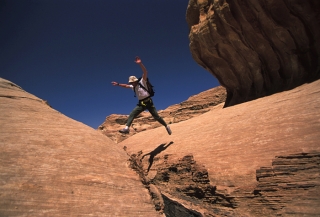 sejour-montagne-escalade-jordanie-randonneur-sautant-par-dessus-un-siq-etroit-mais-profond_mv